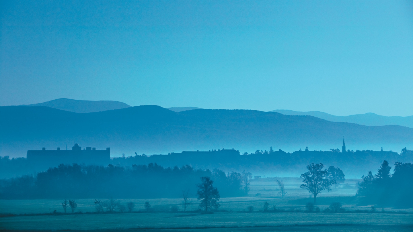 Foggy aerial view of the Middlebury campus with the Green mountains in the background.