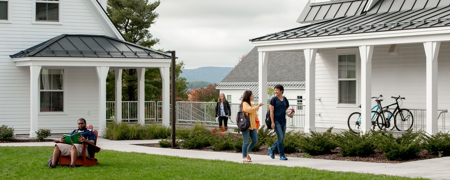 Students walking and sitting outside a residence hall.