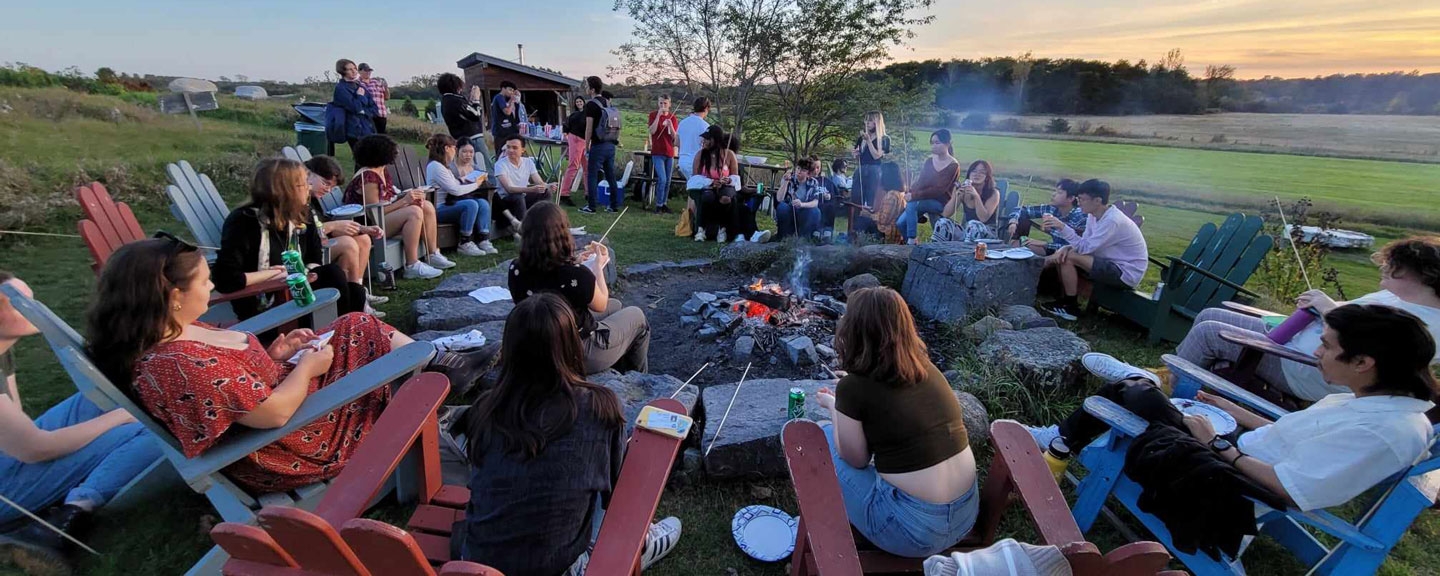 Students gathered around a fire at the Knoll garden.