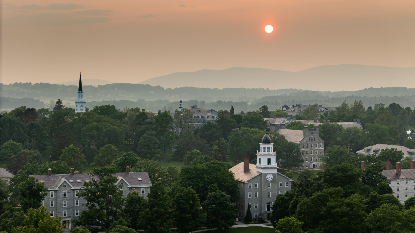 Aerial Image of Middlebury campus with sun and mountains in the background