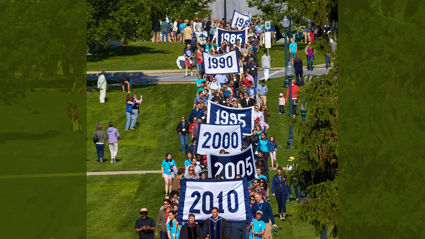 Convocation parade at Reunion, with banners from classes between 2010-1985 visible