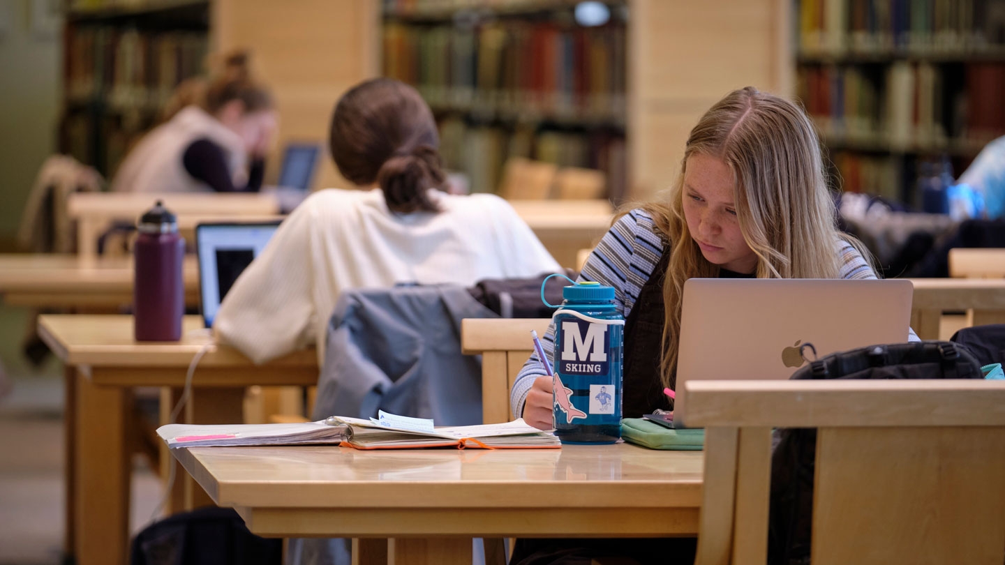 students studying at tables in the library