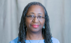 headshot of Beverly Moss, shoulder-length hair in tight twists, wearing a light-blue top