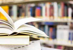 Open book in a library atop a stack of books