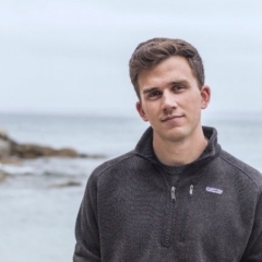 Head shot of Newhouse standing by the ocean shore