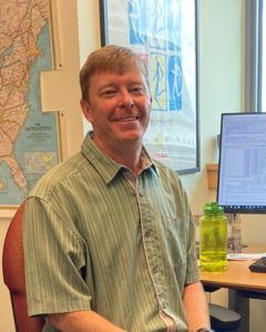 Pete Nelson sitting at his desk with a map on the wall