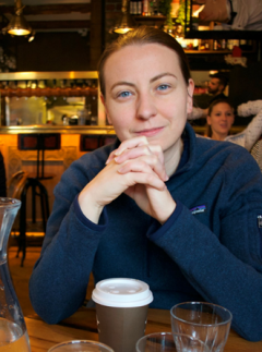 woman in blue shirt sitting at table smiling