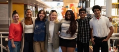 A group of seven students standing arm in arm and smiling at the camera. 