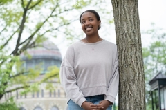 Mariah Jackson '27 stands outside, leaning against a tree and smiling.