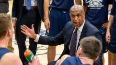 Coach Jeff Brown on the sidelines of a Basketball game talking to players.