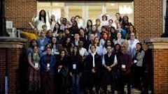 Large group of convening participants stand on steps for a photo