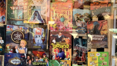 A shop window with various comics and magazines in Hebrew.