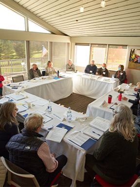 alumni volunteers seated in a square under the peaked ceiling of the Kirk Center