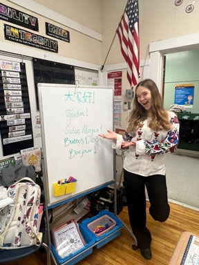 A student in front of a white board with welcome in several languages.