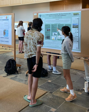 student stands in front of symposium poster explaining it to another student