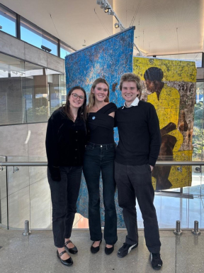 Three students stand in front of an art installation they curated.