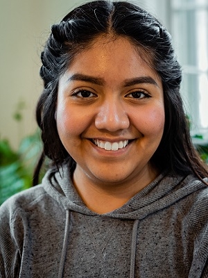 Alondra Carmona wears a gray sweatshirt and smiles at the camera. 