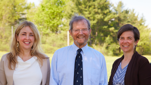 Professors Caitlin Knowles Myers and Sarah Stroup smiling with Hugh Marlow ’57 between them