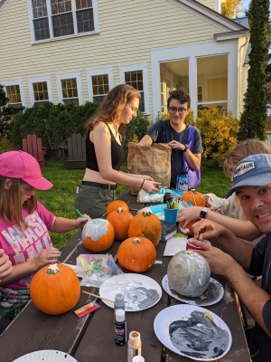 Members of the Yellow House and Yellow House Community Club paint pumpkins at a picnice table outside of the CCE.