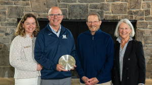 Pam and Erin Quinn with Hugh and Barbara Marlow, smiling. Erin holds a silvery engraved plate.