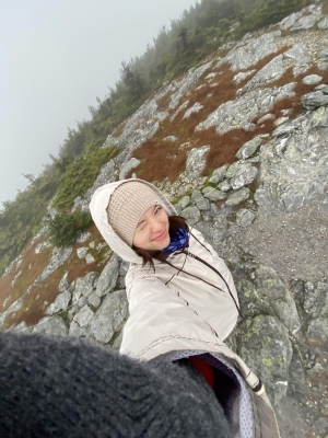 A high angle selfie of a person in a white coat and a white cap.