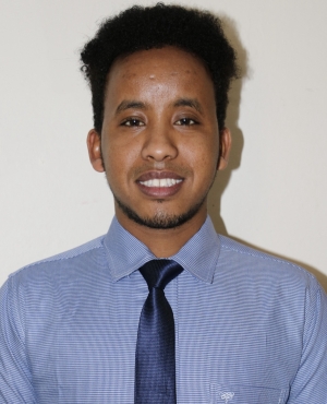 A person in a blue shirt and blue tie is smiling.