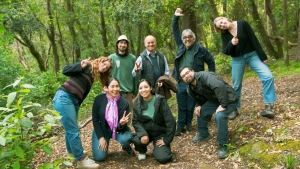 a group of young people pose for a photo in a lush green forest