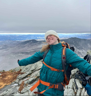 Person wearing a backpack on a mountaintop