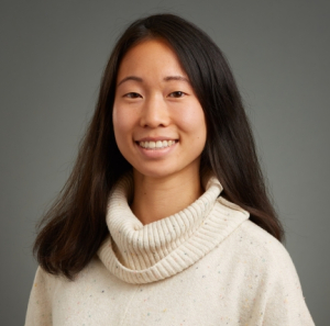 Becky Tang, Long, dark, straight hair wearing a white cowl sweater