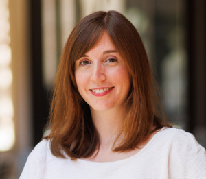 Karen Nershi, straight, brown, shoulder length hair. Wearing white shirt with round neck