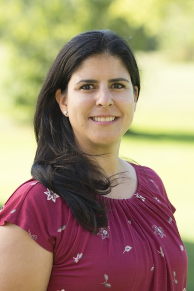 Profile photo of a woman with long brown hair and maroon shirt standing outside