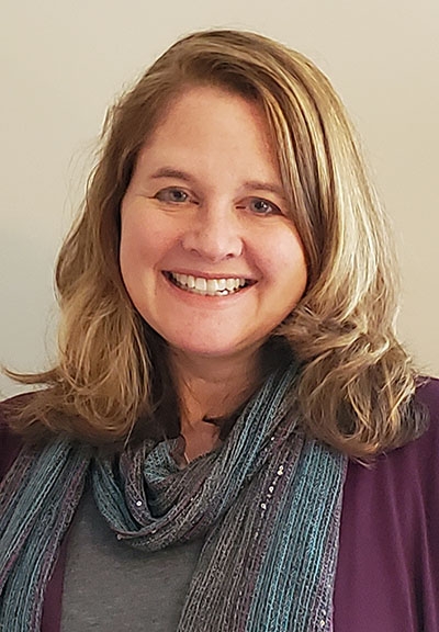 Jenny Orten smiling with a stripe scarf 