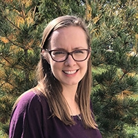 Michaela Kubacki smiling in front of an evergreen tree