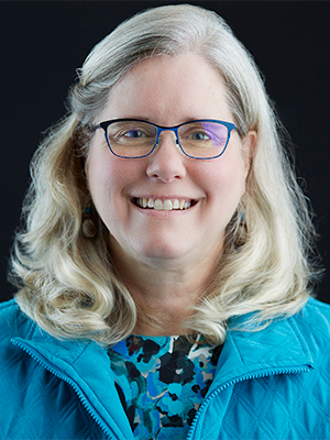 2021headshot of Lyn DeGraff, wearing a light blue vest over a flowered shirt