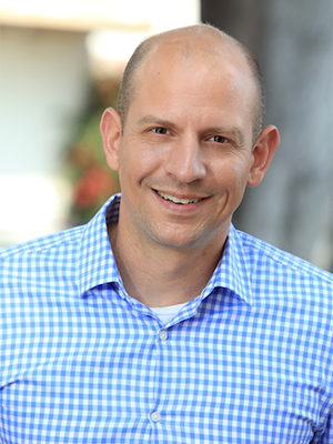 Jason Blazakis in light blue and white checked button-up shirt