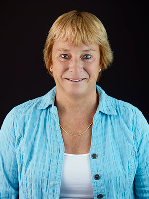 Linda Quesnel in baby blue knit sweater over a white top