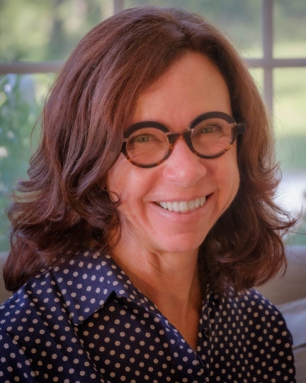 Kristie, wearing a blue shirt with white polka dots, smiling at the camera