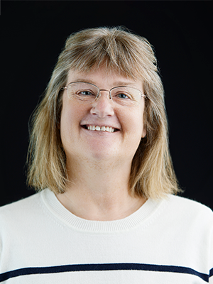 2023 Headshot of Carol Grant, wearing a cream sweater with a blue stripe
