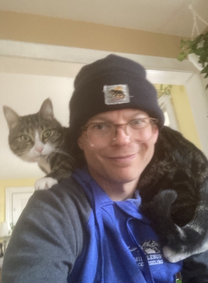 Picture of Nick Parrish, counselor, with cat on their shoulders