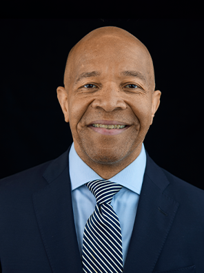 Headshot of Mitchell Patterson in dark navy suit over light blue shirt and striped tie