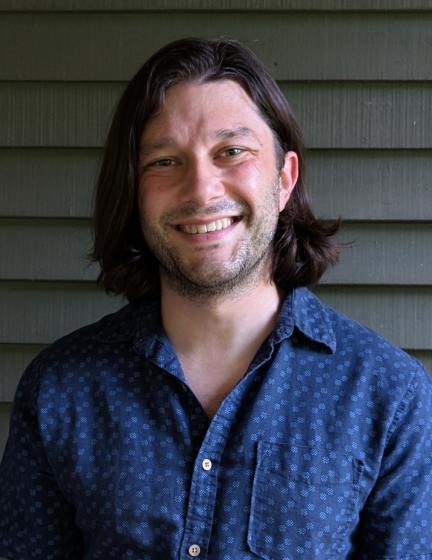 A smiling person with almost shoulder length hair