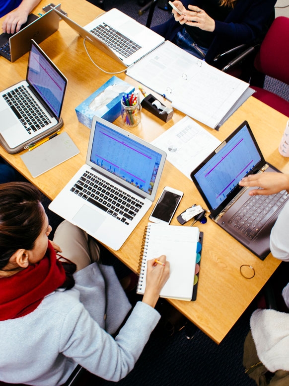 Grad students around a table collaborate on a data project.