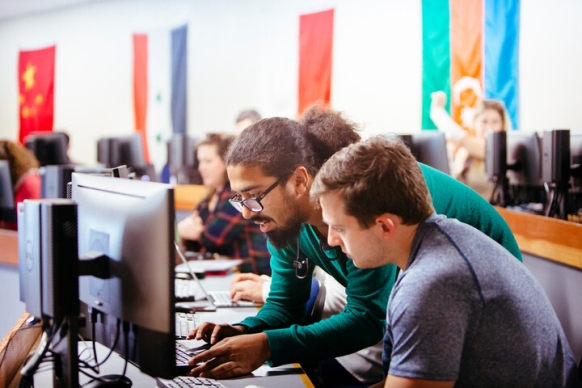 Two students look at a computer during class together