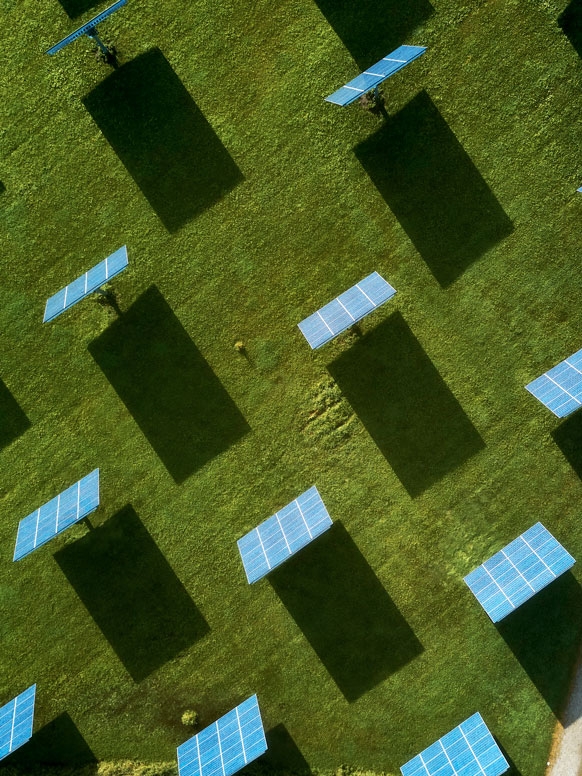 Aerial view of a large solar array in a field of green grass.