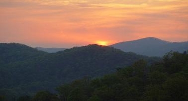 sunrise with pink and orange sky over dark hills