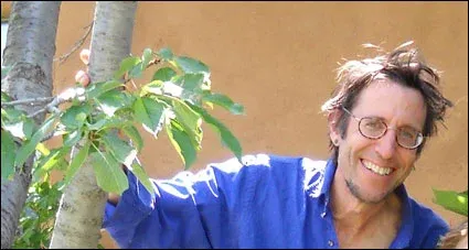 smiling man with mussed hair with his hand on bamboo plant