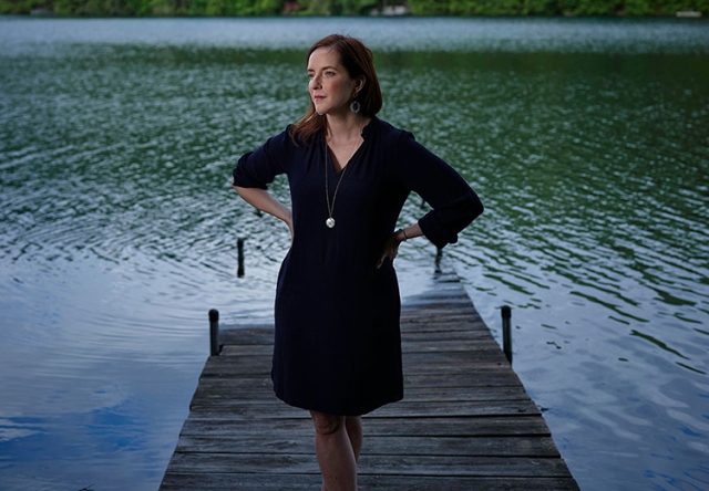 Rebecca Makkai MA ’04 standing on the dock of a lake with her hands on her hips