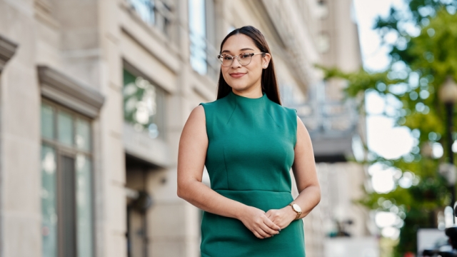 Portrait of Elsa Alvarado ’18 in standing in a Green dress outside.