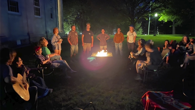Group of Students Gathered around a fire pit at night