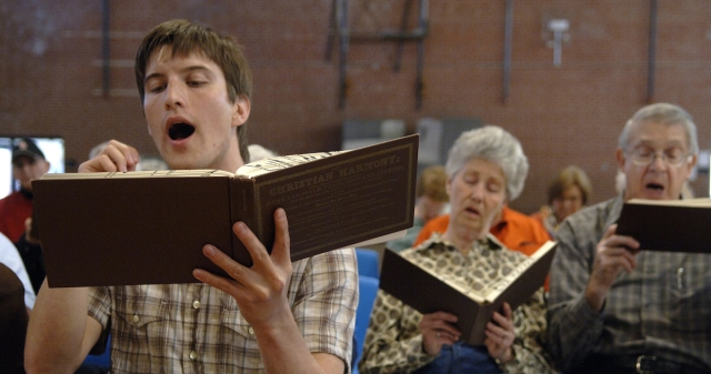 elders and young people singing from songbooks